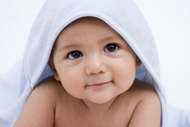 Head shot of baby with blue towel draped over head